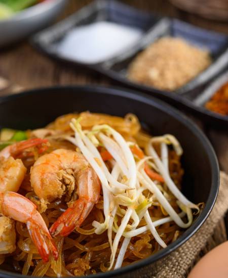 Padthai shrimp in a black bowl with eggs and Seasoning on wooden Padthai shrimp in a black bowl with eggs and Seasoning on wooden table.